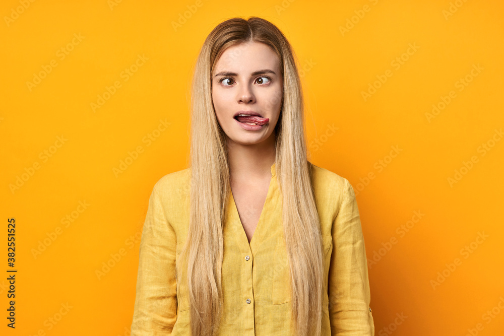 crazy young woman in a yellow shirt on a yellow background. blonde grimaces. crazy young woman in a yellow shirt on a yellow background. blonde grimaces.