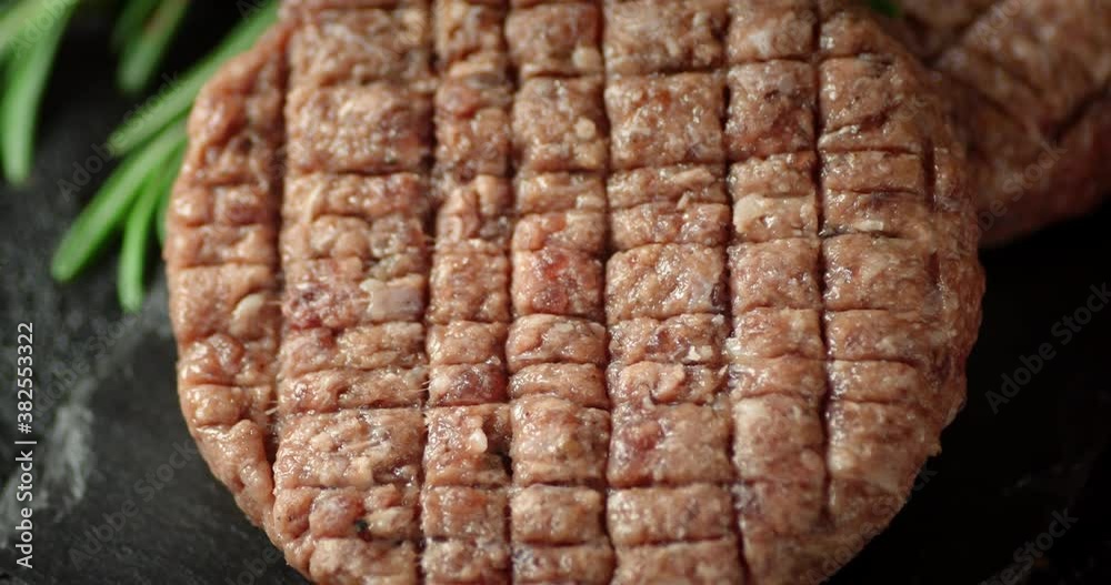 Raw beef burger on a stone board rotates. Raw beef burger on a stone board rotates.