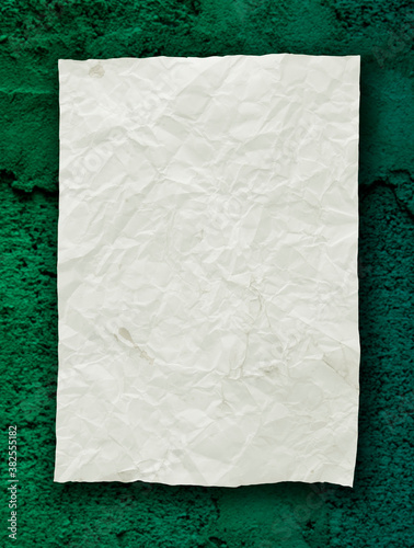 Crumpled paper on green old wall background