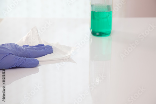 Surface disinfecting home cleaning with sanitizing antibacterial wipes protection against COVID-19 spreading wearing medical blue gloves. Sanitize surfaces prevention in hospitals and public spaces