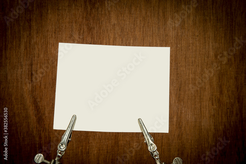 Clamp holding paper note on wood background