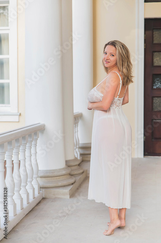 beautiful blonde in a nightgown on the pillared porch at home
