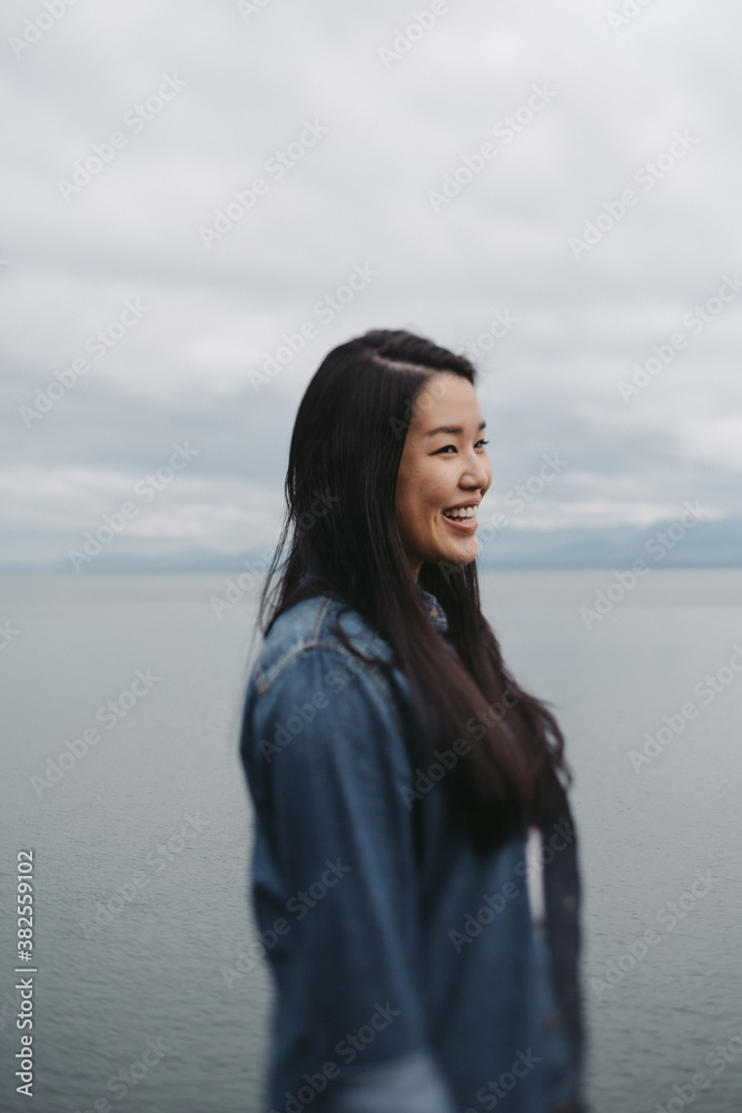 Young, beautiful asian woman smiling near ocean water Young, beautiful asian woman smiling near ocean water