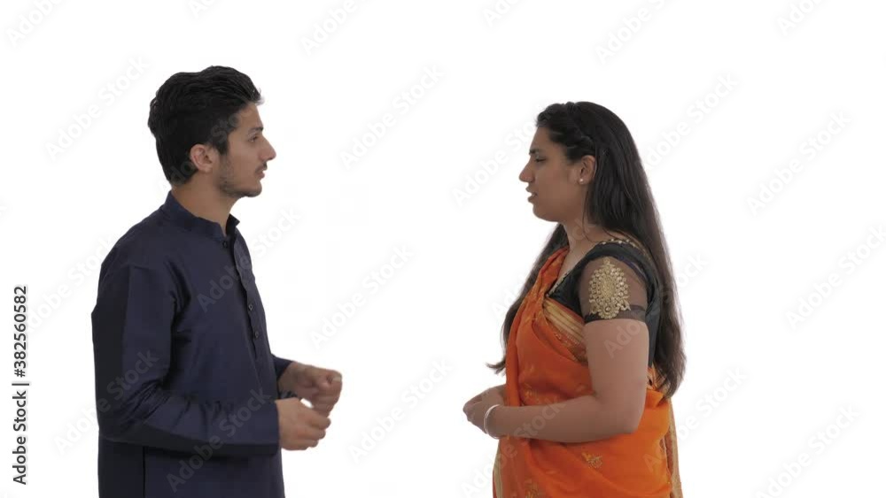 Side view of Indian couple sorting things out. Spouses quarrel, emotionally gesticulating. Man doing aggressive slap gesture. Offended and frightened wife turn away from him. Side view of Indian couple sorting things out. Spouses quarrel, emotionally gesticulating. Man doing aggressive slap gesture. Offended and frightened wife turn away from him.