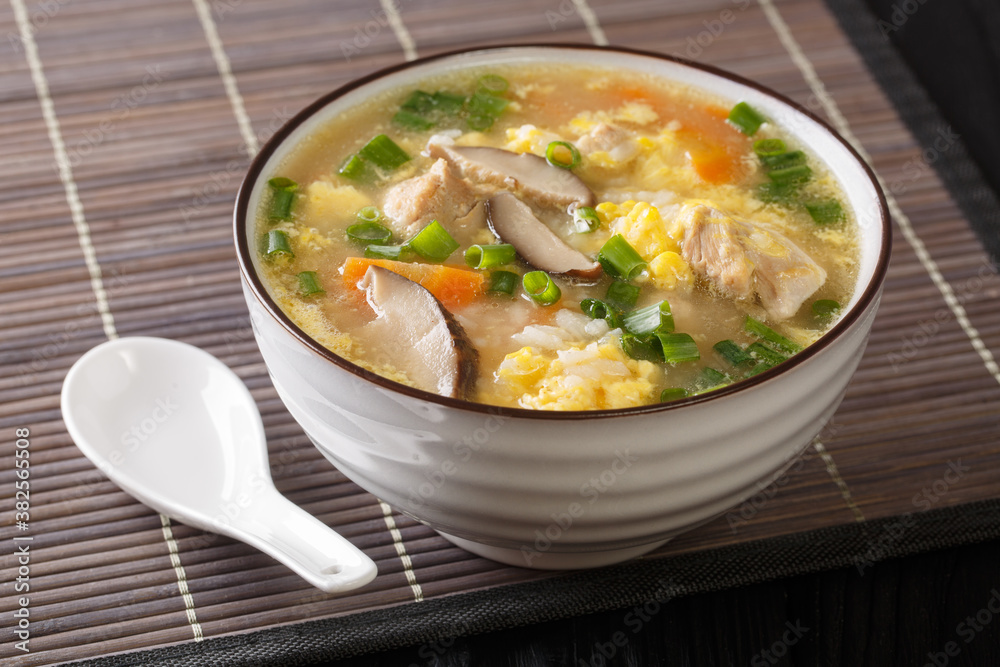 Japanese hot Rice Soup Zosui with chicken, egg and vegetables close-up in a bowl on the table. Horizontal
