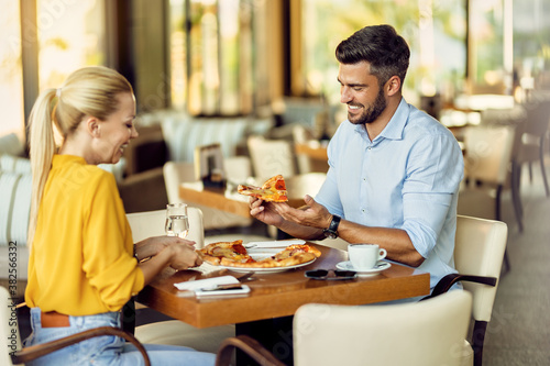 Happy couple eating pizza in a restaurant.