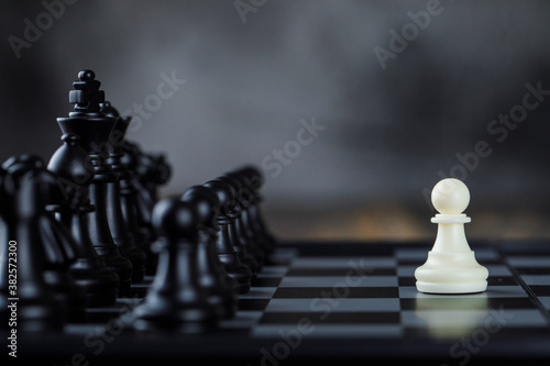 Business strategy concept with figures on chessboard on foggy and wooden background side view.