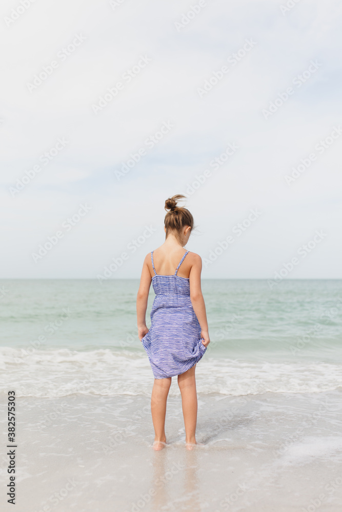 Young girl standing at the waters edge, looking down Young girl standing at the waters edge, looking down