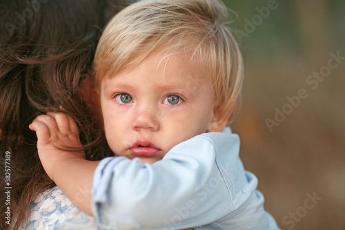 Blonde Hair Blue Eyed Toddler With Teary Eyes being Held photo