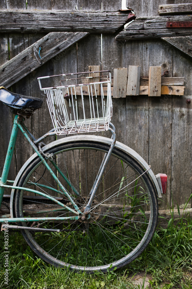 An old bicycle leaning against the wooden fence An old bicycle leaning against the wooden fence