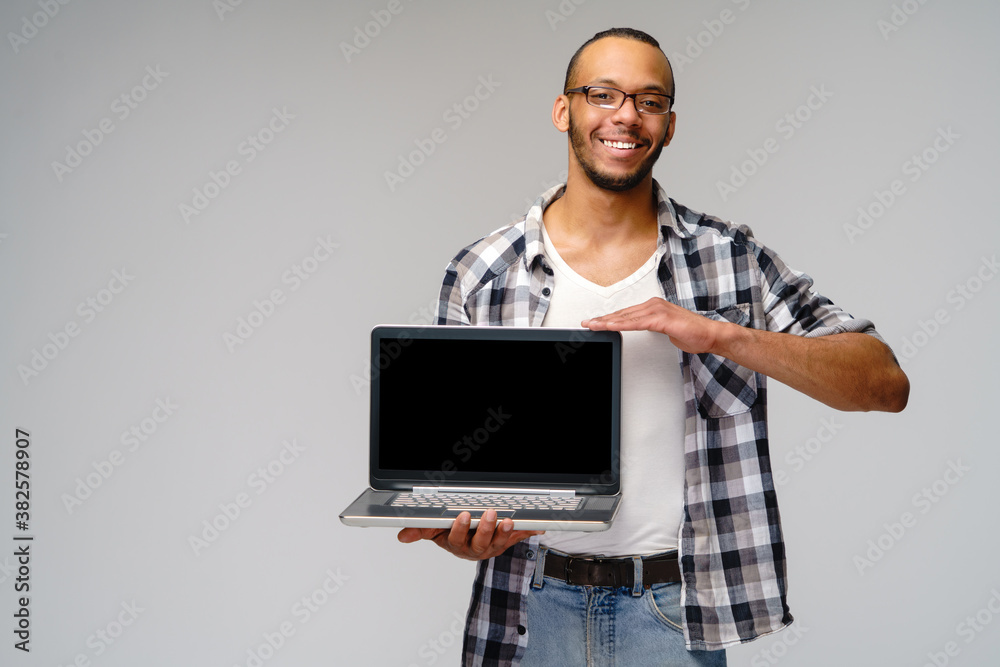 A young african american man holding laptop pc and showing at blank screen A young african american man holding laptop pc and showing at blank screen