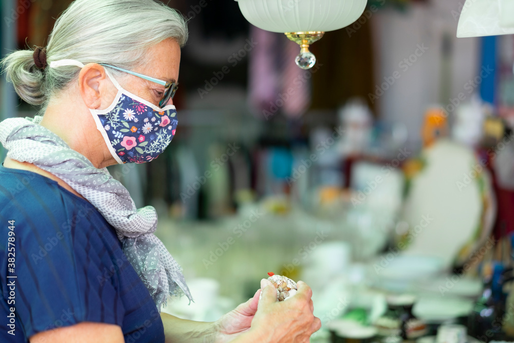 Senior woman wearing flowered mask due to coronavirus while shopping at flea market