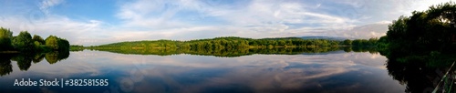 Panoramic view of a calm lake on a sunny summer day © mikhailgrytsiv