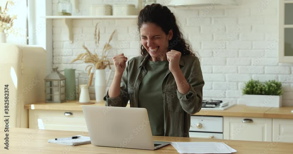 Woman in kitchen using laptop check e-mail read great news feels incredible happy scream with joy raised clenched fists laughing celebrate success. Winner and candid emotions, personal advance concept Woman in kitchen using laptop check e-mail read great news feels incredible happy scream with joy raised clenched fists laughing celebrate success. Winner and candid emotions, personal advance concept