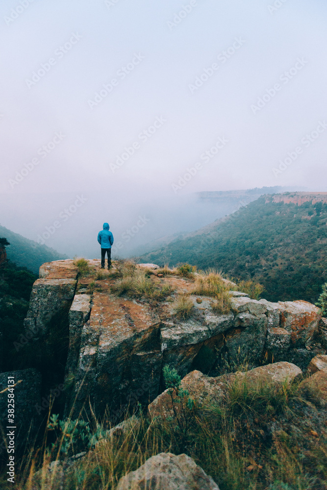 Hiker on a rocky outcrop overlooking a scenic mountain valley Hiker on a rocky outcrop overlooking a scenic mountain valley