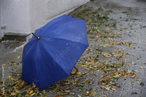 Blue umbrella standing on wet street on a rainy day © bahadirbermekphoto