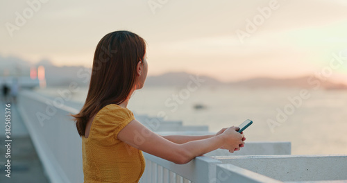 Woman hold with cellphone and look at the sunset