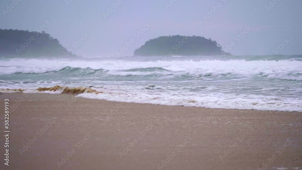 Landscapes view of waves breaking on beach sand and the sky on a stormy rainy season Landscapes view of waves breaking on beach sand and the sky on a stormy rainy season