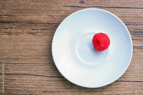 raspberry berry in a white plate on a wooden table