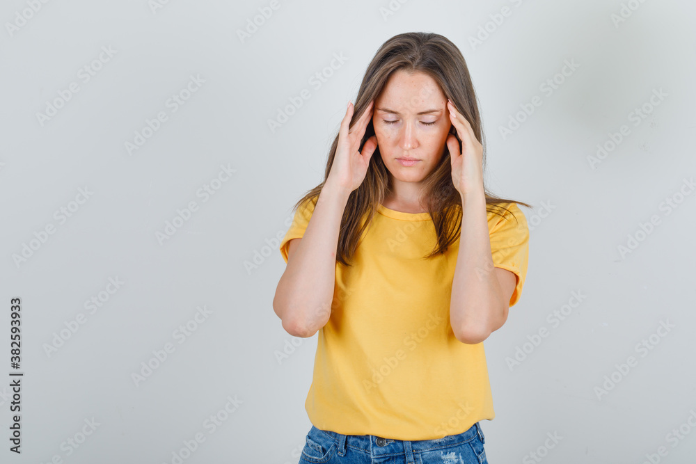 Young woman suffering from headache in t-shirt, shorts and looking tired. front view. Young woman suffering from headache in t-shirt, shorts and looking tired. front view.