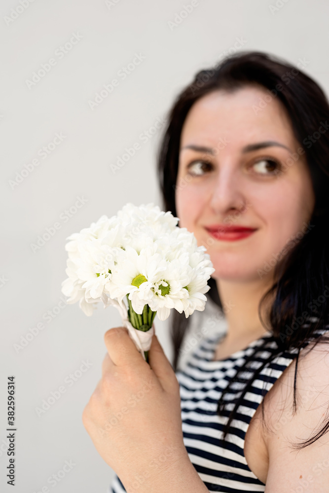 Happy young woman holding a bouquet of flowers on a gray solid background
