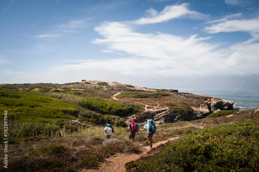 Three Hikers walk along the sand on dunes