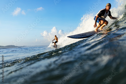 Three young adult surfers rides the wave of the ocean at the surf spot. High quality photo