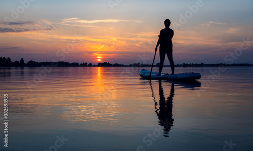 Silhouette of a person on a SUP board sunset