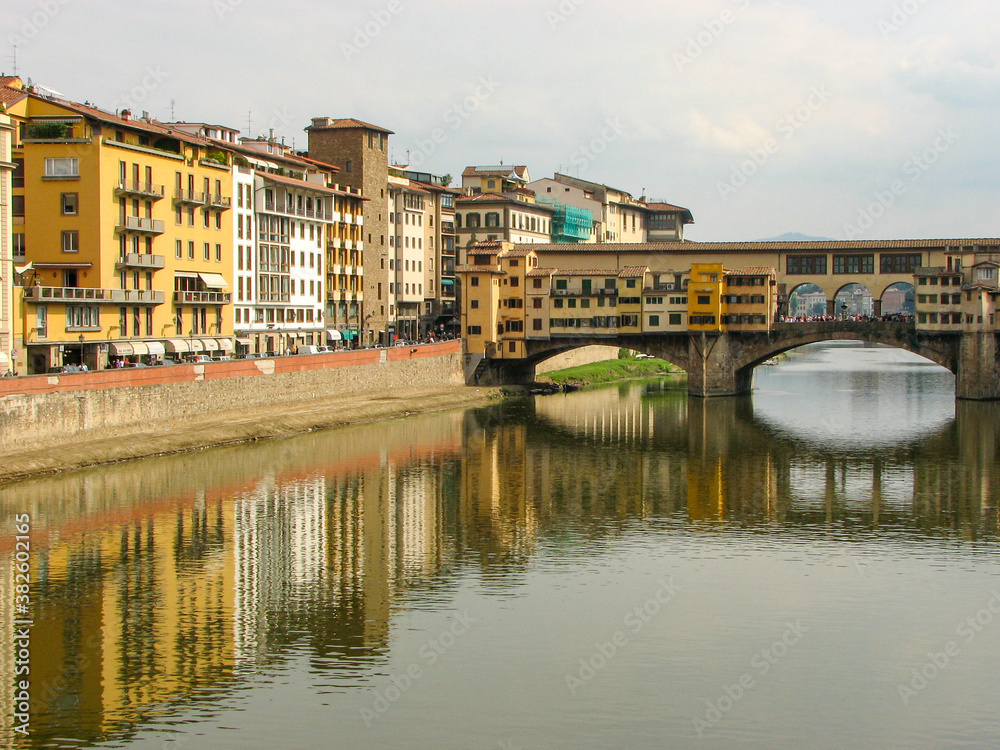 Florence, Italy - October 1 2006 - Ponte Vecchio, a medieval stone covered bridge over the Arno River. It was first built in 996 and is known for shops lining it. Image has copy space.