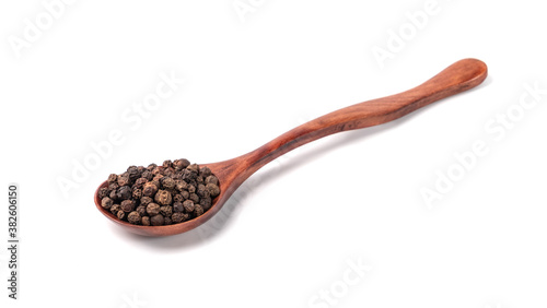 Black pepper in a wooden spoon on a white background.
