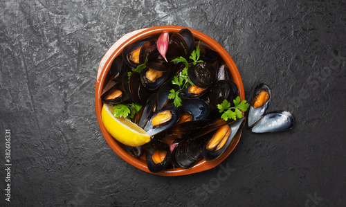 Boiled mussels in in a bowl on dark background