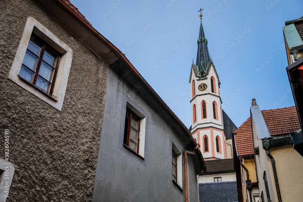 Medieval narrow street with colorful renaissance historical buildings, tower of the St. Vitus Church in the center of Cesky Krumlov, South Bohemia, Czech Republic