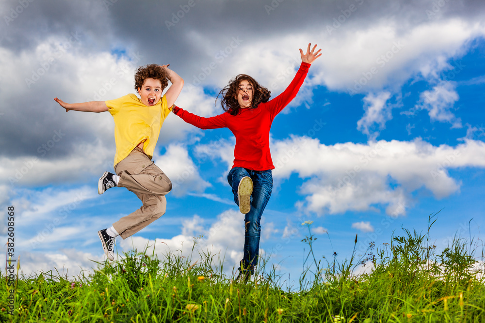 Girl and boy running, jumping against blue sky
Girl and boy running, jumping against blue sky