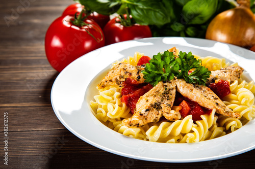 Chicken ragout with fusilli on wooden table 