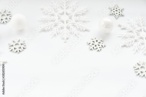 Pattern made of white balls and snowflakes on white background.