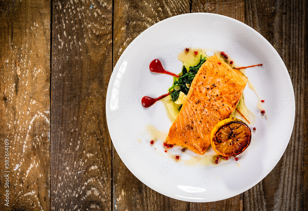 Fried salmon fillet with lemon served on wooden table Fried salmon fillet with lemon served on wooden table