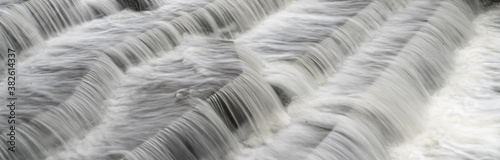 White Water flowing over weir low-level view at long exposure to give blurred motion effects