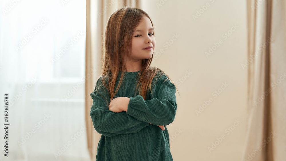 A little cute girl suspecting something with her hands crossed on her chest and eyes slightly closed A little cute girl suspecting something with her hands crossed on her chest and eyes slightly closed