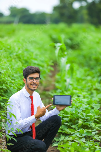 Technology and people concept, Young indian agronomist showing tablet at field