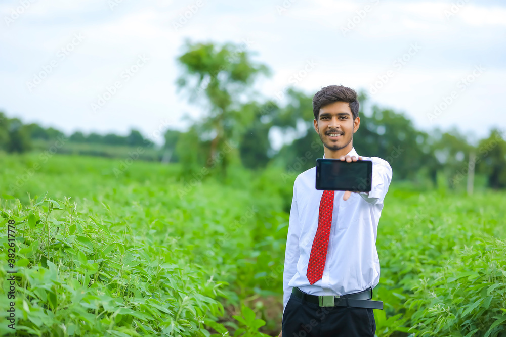 Technology and people concept, Young indian agronomist showing tablet at field Technology and people concept, Young indian agronomist showing tablet at field
