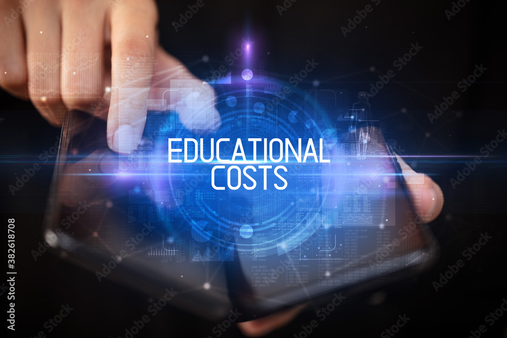 Fototapeta premium Young man holding a foldable smartphone with EDUCATIONAL COSTS inscription, educational concept