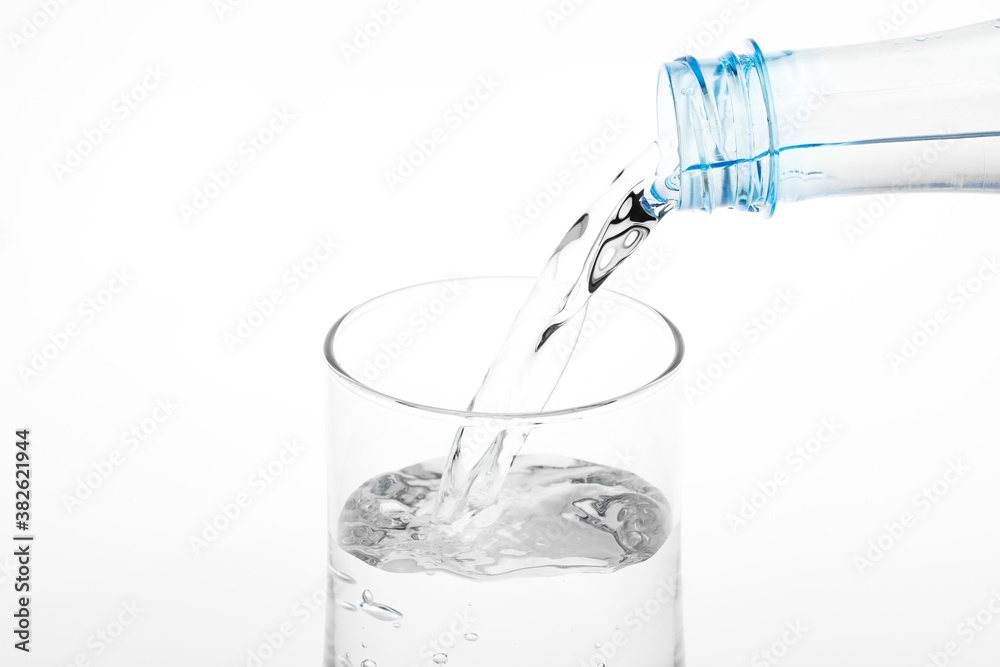 Pouring water from plastic bottle into glass on white background. Pouring water from plastic bottle into glass on white background.