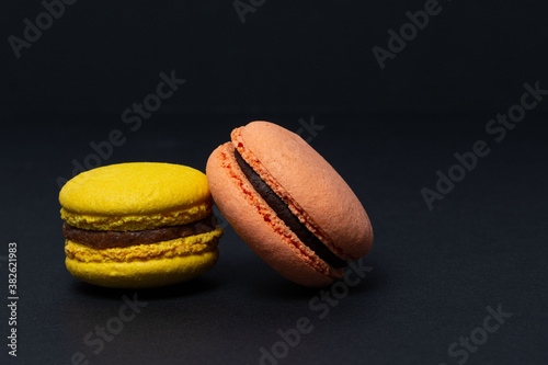 Appetizing macaroni of red and yellow colors are located on a black background. Side view