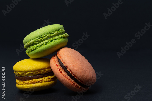 Appetizing macaroni of red, greem and yellow colors are located on a black background. Side view