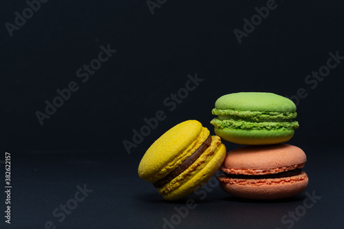 Macaroni, red, yellow, green, are stacked one on top of the other in the form of a tower on a black background