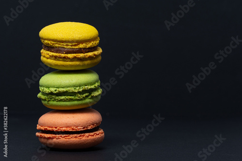 Macaroni of different colors stand one on top of the other in the form of a tower on a black background