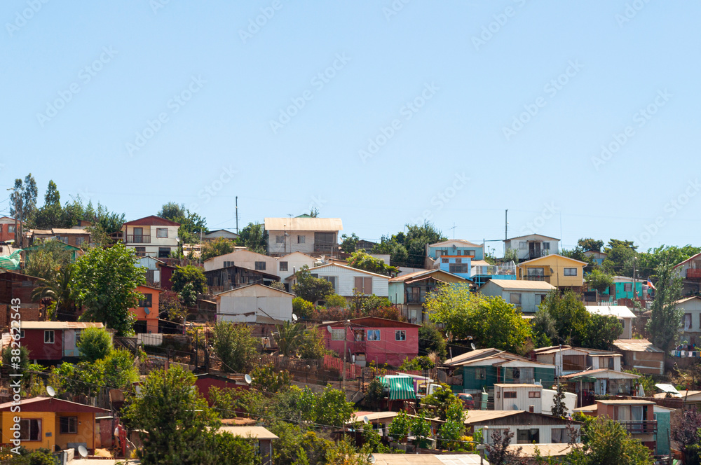 Bunch of houses on a hill in chile. Rudimentary and poor houses, colorful, between trees.