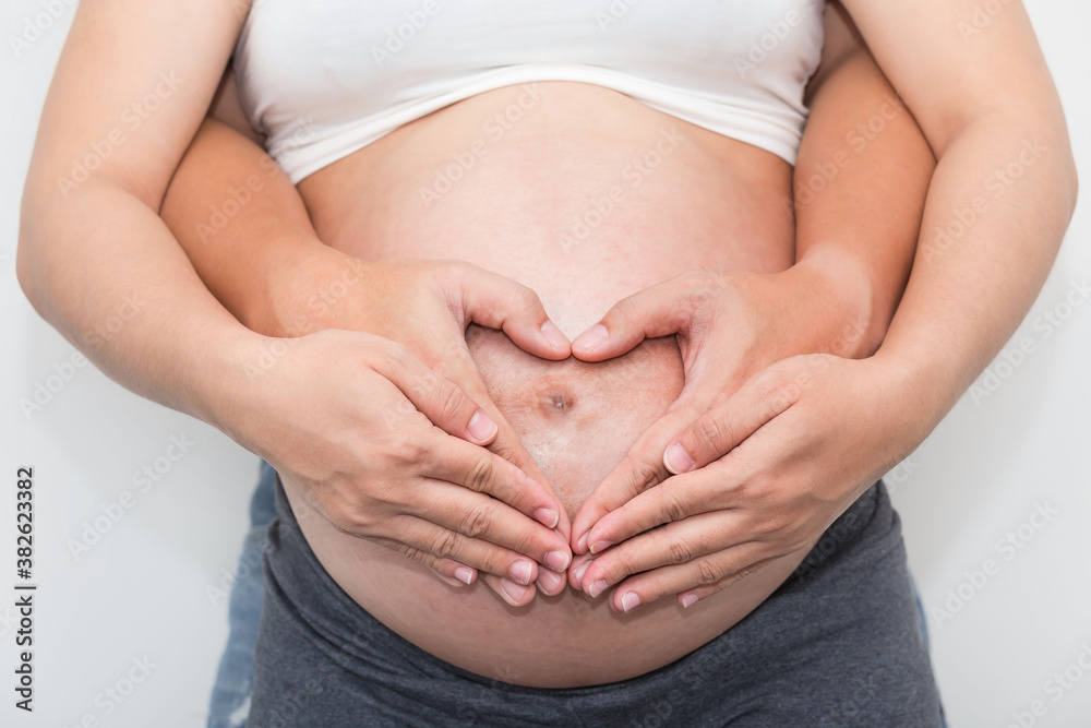 Love couple image with a beautiful pregnant woman and her husband hugging the tummy Love couple image with a beautiful pregnant woman and her husband hugging the tummy
