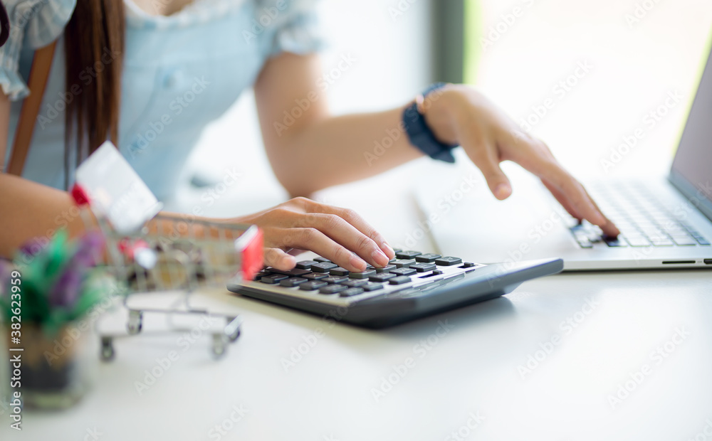 Close up of beautiful woman's hand using calculator keyboard. Laptop is standing by on the desk. Concept of accountant's work Close up of beautiful woman's hand using calculator keyboard. Laptop is standing by on the desk. Concept of accountant's work