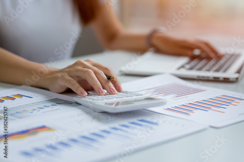Close up of businesswoman Accounting using calculating income-expenditure and analyzing real estate investment data report Financial and tax systems concept. 